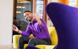 homem-feliz-vestido-com-roupa-social-sentado-em-um-sofa-amarelo