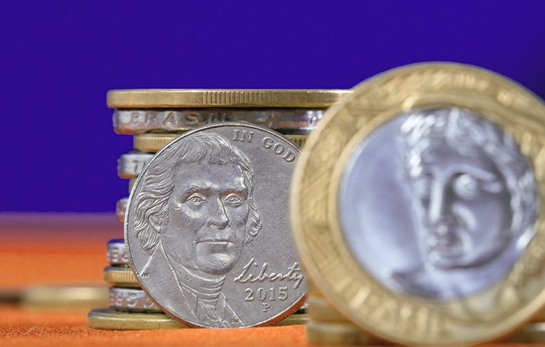 Pilha de moedas brasileiras e uruguaias representando a crise entre Uruguai e Mercosul. 
