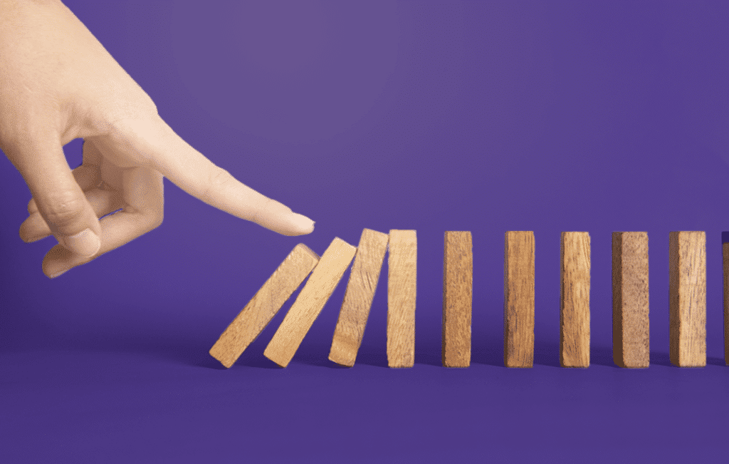 Dedo de um homem emburrando bloquinhos que estão em sequência um do outro. 